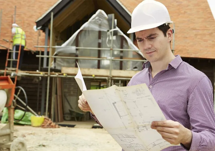 Builder reviewing plans at a construction site