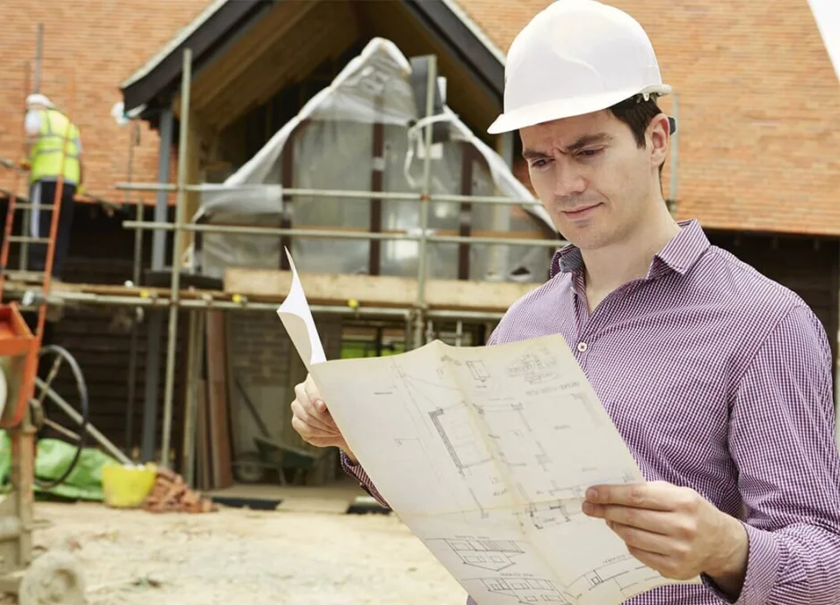 Builder reviewing plans at a construction site